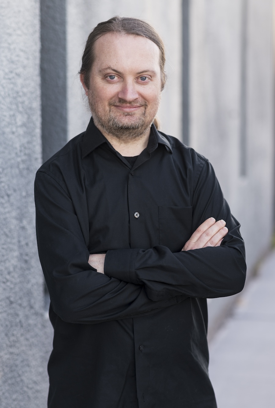 colour photograph of Stephen Moylan standing, smiling, wearing a black shirt. Photo Credit: 2024 Alan Moyle (Photobat)